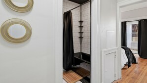 A modern bathroom with a shower, a white tiled wall, and a wooden floor. - Newly renovated 2-bedroom apartment in quiet Historic Detroit neighborhood (Detroit)