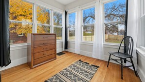 A room with large windows, a wooden dresser, a chair, and a patterned rug. - Newly renovated 2-bedroom apartment in quiet Historic Detroit neighborhood (Detroit)