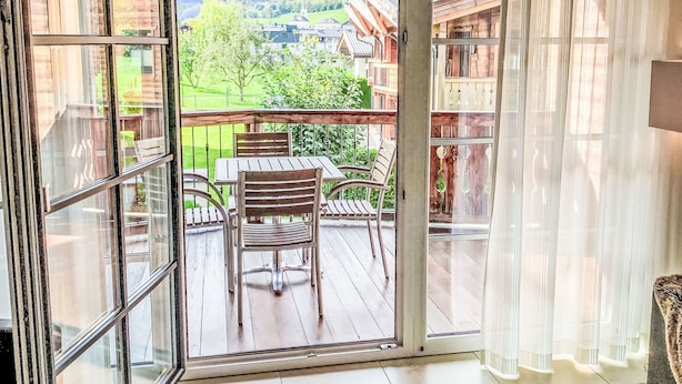 Et værelse med en skydedør til en balkon med et træbord og stole.