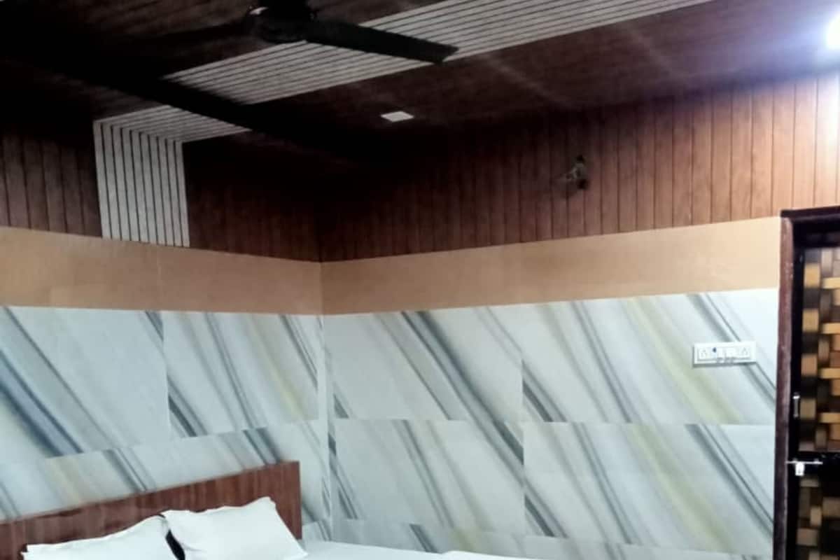 Une chambre à coucher avec un cadre de lit en bois, du linge de lit blanc et des murs à motifs de marbre.
