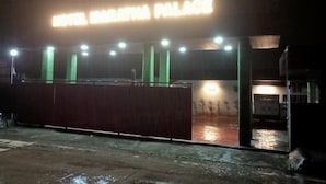 Entrada de un hotel con un letrero de neón que dice "HOTEL MARATHWA PALACE" y suelo mojado que indica lluvia reciente.