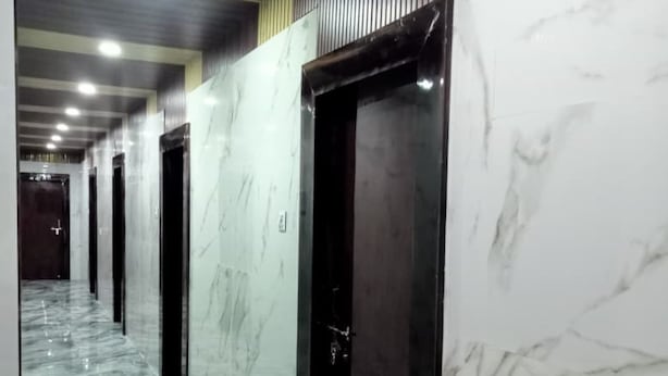 Un pasillo con suelo de mármol y puertas que conduce a habitaciones.
