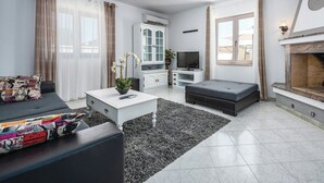Ein modernes Wohnzimmer mit einer Couch, einem Couchtisch, einem Fernseher und einem Kamin.