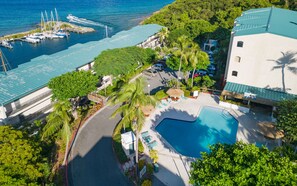 A resort with a swimming pool, a dock with boats, and lush greenery. - 2 Pools, Dining | Walk to Beach | Sapphire Village (St. Thomas)
