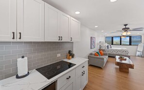 A modern kitchen with white cabinets, a grey tiled backsplash, and a central island with a stove. - 2 Pools, Dining | Walk to Beach | Sapphire Village (St. Thomas)