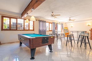 A pool table in a room with ceiling fans, bar stools, and a table with a menu board. - HOTEL ANTARES HAB. ESTANDARD - Cozy hotel in the center of Cala d'Or. Free Wi-Fi. (Cala d'Or)