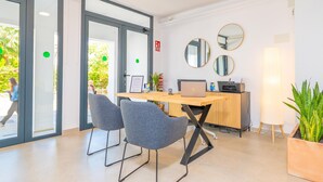Un espace de bureau moderne comprenant un bureau, deux chaises, un ordinateur portable, une imprimante et une plante en pot.