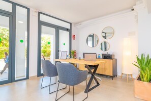 Een moderne kantoorruimte met een bureau, twee stoelen, een laptop, een printer en een potplant.