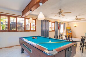 Ein Billardtisch mit Kugeln, Deckenventilatoren und eine Bar mit Hockern.