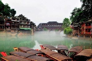 A traditional Chinese courtyard with a river, wooden boats, and buildings with classic architecture.