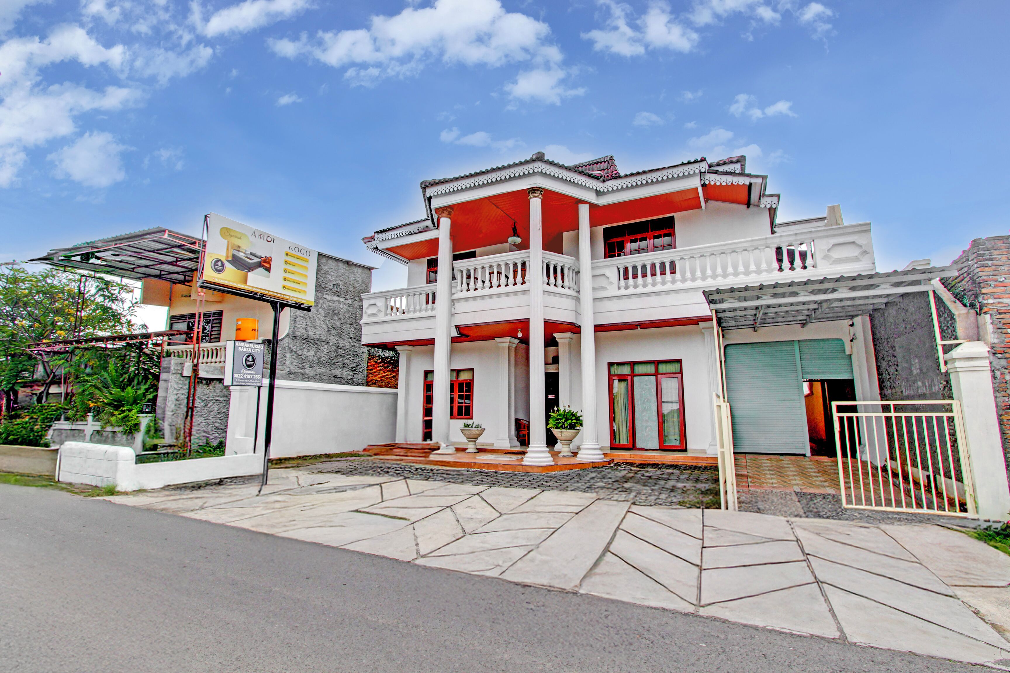 A two-story house with a balcony, a garage, and a gated entrance.