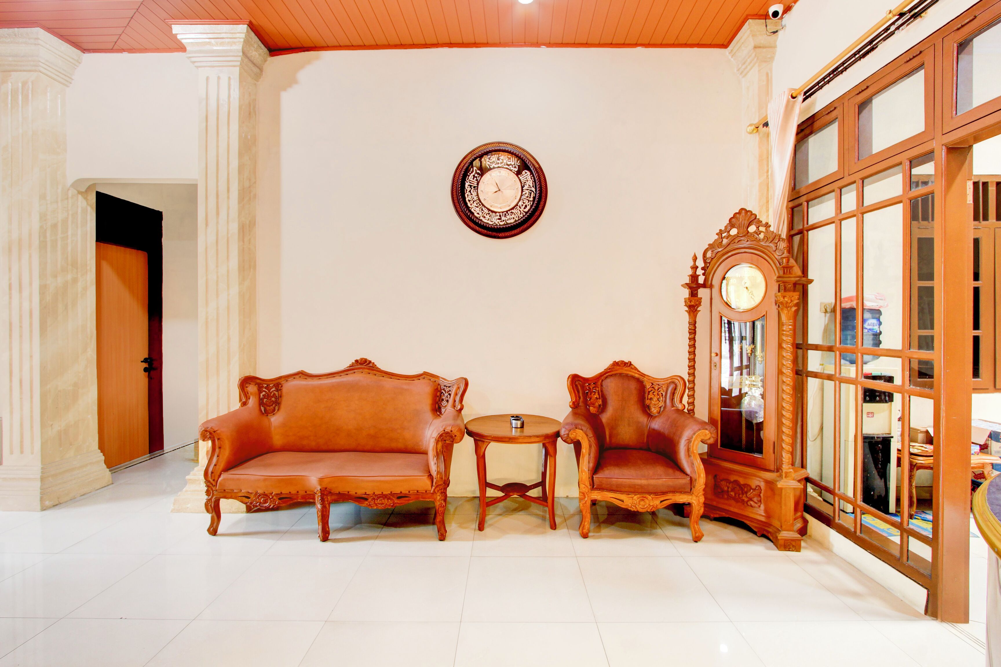 Um quarto com duas sofás elaboradas, uma mesinha redonda e um relógio de madeira grande na parede.