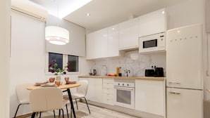 A modern kitchen with white cabinetry, a built-in microwave, a stainless steel oven, and a refrigerator. - Apartment + Workspace Chamberí (Madrid)