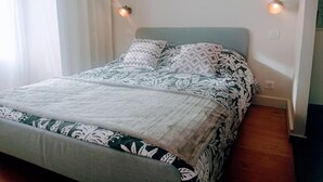 Een bed met beddengoed met een patroon, een hoofdbord en twee wandlampen.