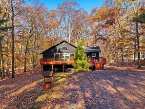 A cabin with a deck, a covered porch, and a small attached structure.