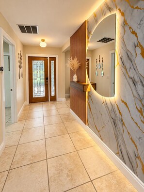A hallway with a marble wall, a wooden panel, and a door with a glass window. - Moon Luxury Retreat/Heated Pool (Sarasota)