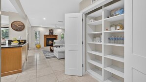 Een moderne keuken met een inbouwpantry, een eetgedeelte met een open haard, en een woonkamer met een bank en een salontafel.