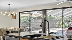 Een moderne keuken met een groot kookeiland, een inbouwvaatwasser, en een eethoek met een tafel en stoelen.