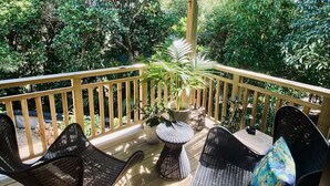 A wooden deck with outdoor furniture, surrounded by lush greenery. - Omiha Exclusive Retreat (Waiheke Island)
