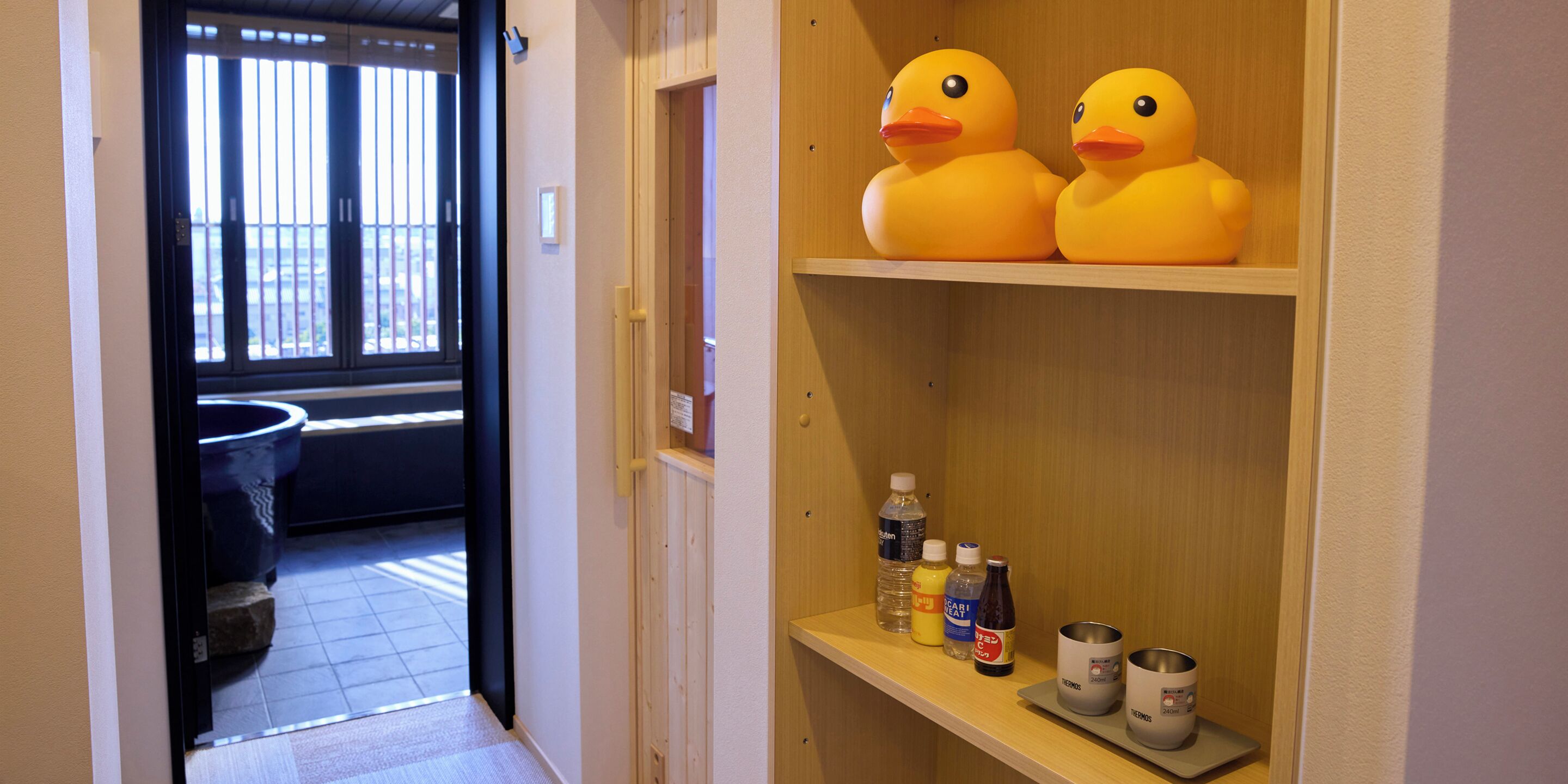 A hallway with a wooden shelf holding two rubber ducks and various bottles.