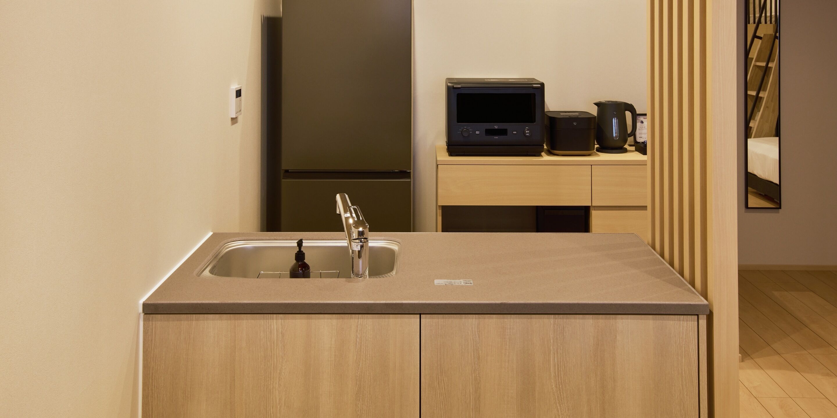 Una cocina moderna con un fregadero, un microondas y una tetera sobre una encimera de madera.