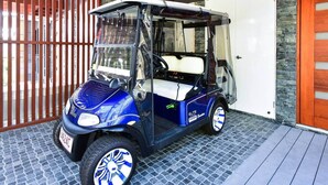 A compact, blue and white golf cart parked on a cobblestone surface. - Hidden Cove 17 (Hamilton Island)