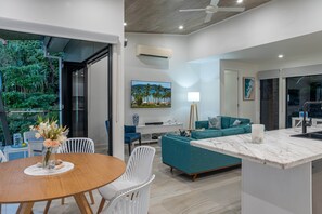 A modern living room with a dining area, a sofa set, and a kitchen island. - Hidden Cove 17 (Hamilton Island)