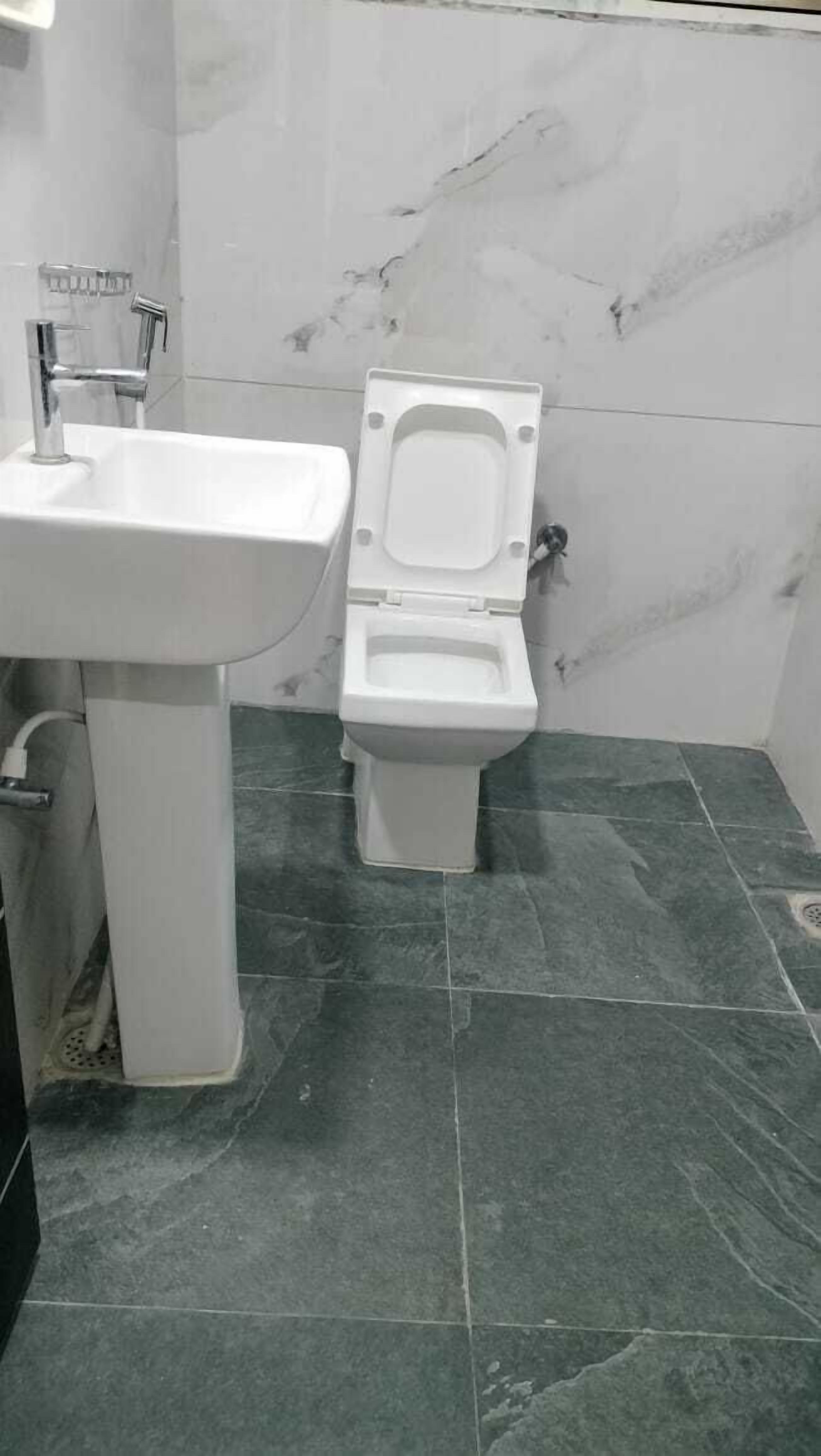 Et badeværelse med en hvid vask og et hvidt toilet.