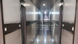 A corridor with a polished floor, metallic doors, and a wooden ceiling. - Hotel Palika (Hassan)