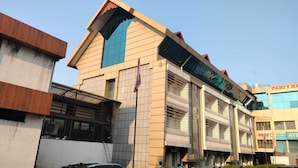 A hotel with a modern design, featuring a prominent entrance with a glass facade and a red roof. - Hotel Palika (Hassan)