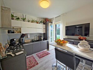Une cuisine moderne équipée d’une cuisinière à gaz, d’une machine à café et d’un téléviseur fixé au-dessus du plan de travail.