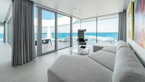 En moderne stue med en stor glasdør, der fører ud til en balkon med udsigt over havet.