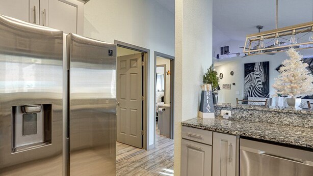 A modern kitchen with stainless steel appliances, a granite countertop, and a view into the adjacent living area.