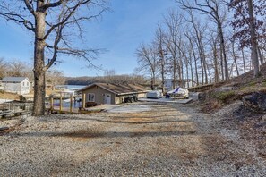 A gravel driveway leading to a house with a covered porch, a small shed, and a tractor.