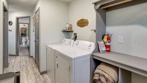 A laundry area with a washer and dryer, a shelf with cleaning supplies, and a fire extinguisher.