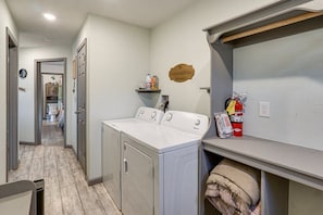 A laundry area with a washer and dryer, a shelf with cleaning supplies, and a fire extinguisher.