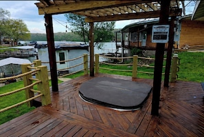 A wooden deck with a hot tub, a wooden cabin, and a view of the lake.