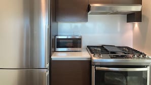 A compact kitchen with a stainless steel refrigerator, microwave, gas stove, and oven.