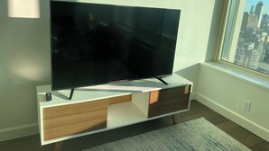 A flat-screen TV on a white and wooden TV stand in a room with a large window.