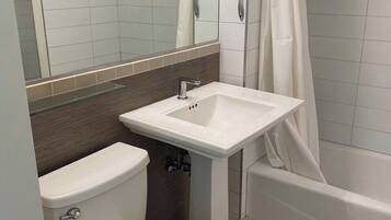 Ein Badezimmer mit Toilette, Waschbecken, Dusche und Spiegel.