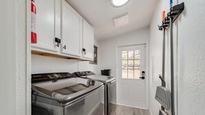 A compact kitchen with stainless steel appliances, a white door, and a window. - Newly Remodeled Mobile Home The Green Showcase! (Mineral Wells)