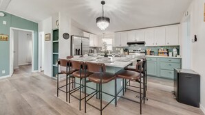 A modern kitchen with a central island, stainless steel appliances, and a chandelier. - Newly Remodeled Mobile Home The Green Showcase! (Mineral Wells)
