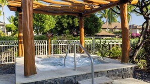 Un área de hidromasaje con una pérgola de madera, escalones de piedra y barandilla metálica.