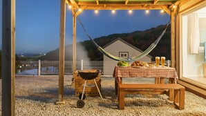 An outdoor patio with a table set for dining, a hammock, and a barbecue grill. - Gangneung Dawon-hill Pension (Gangneung)
