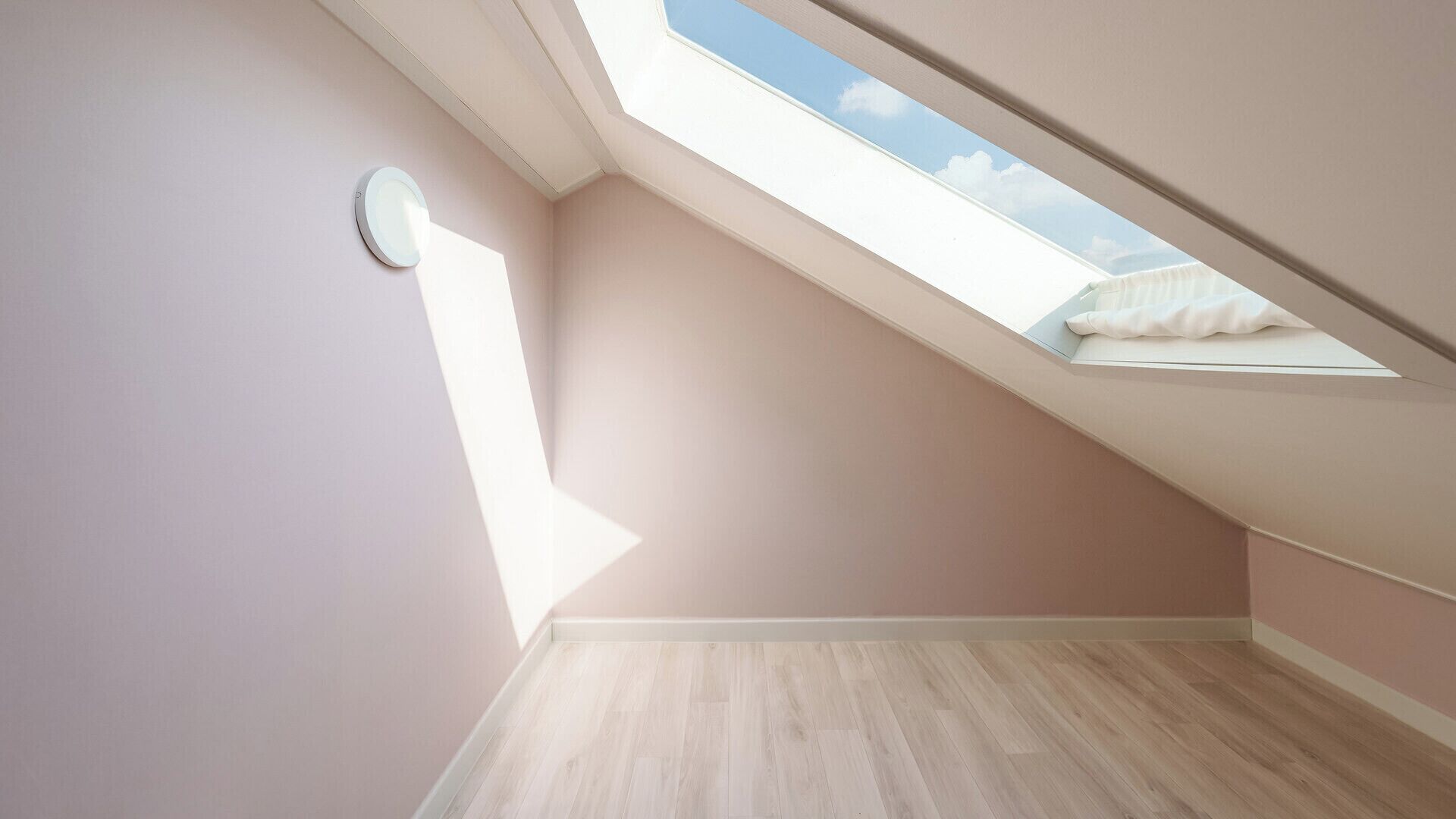 A room with a sloped ceiling and a skylight.