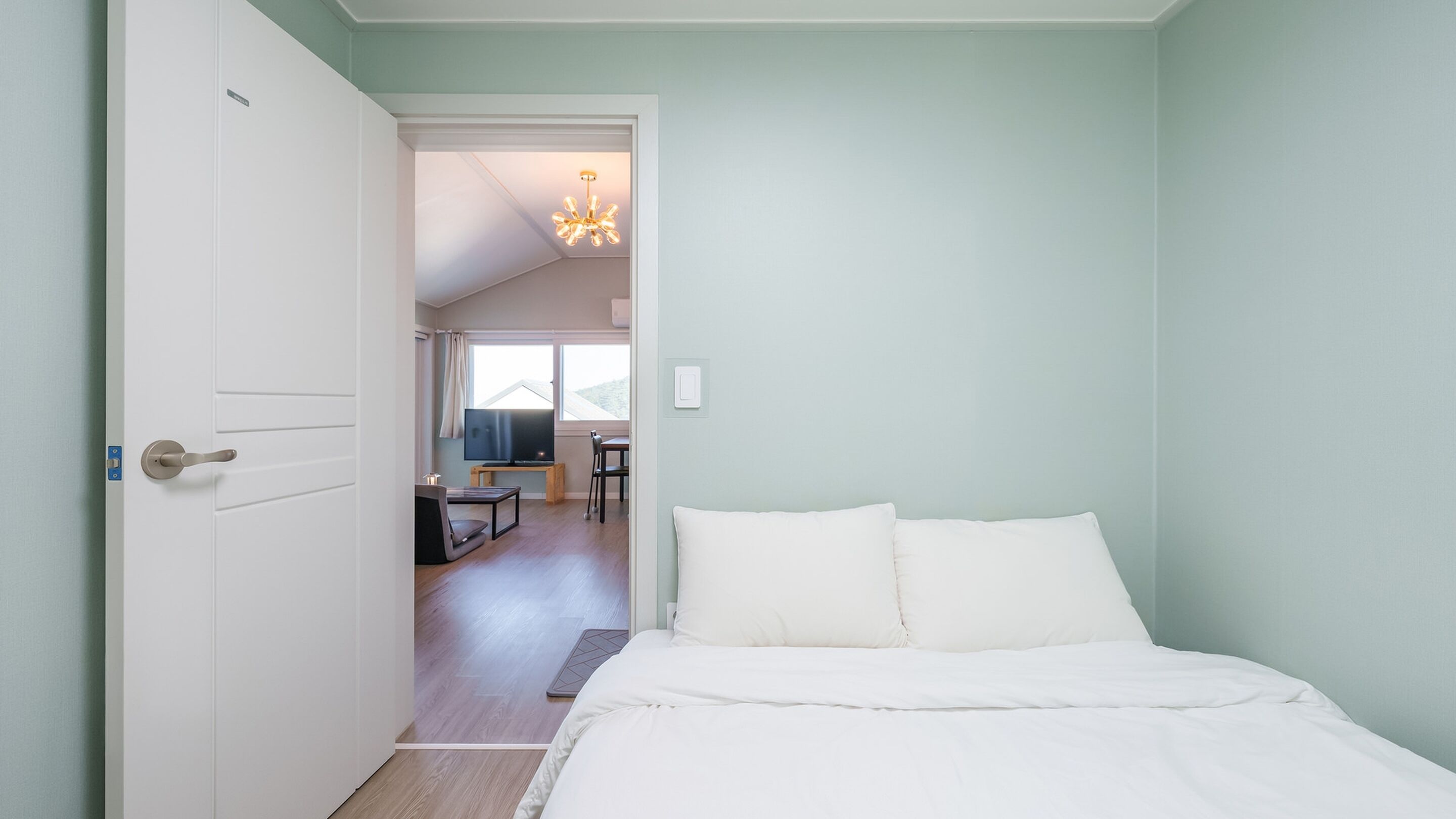 Een slaapkamer met een bed, een televisie en een zithoek met een tafel en stoelen.