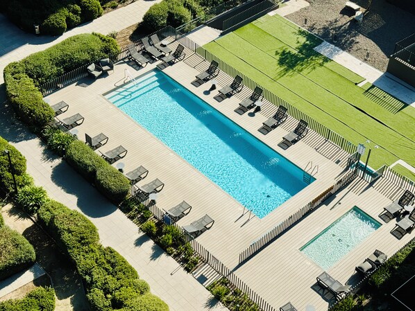 A large rectangular swimming pool with adjacent lounge areas and a grassy field. - Aire Acond. | Estacionamiento | El mejor lugar (Santiago)