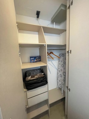 Een inloopkast met kledingroede, planken en een koffer.