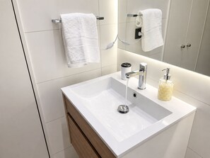 A modern bathroom with a white sink, chrome faucet, and a soap dispenser. - Aire Acond. | Estacionamiento | El mejor lugar (Santiago)