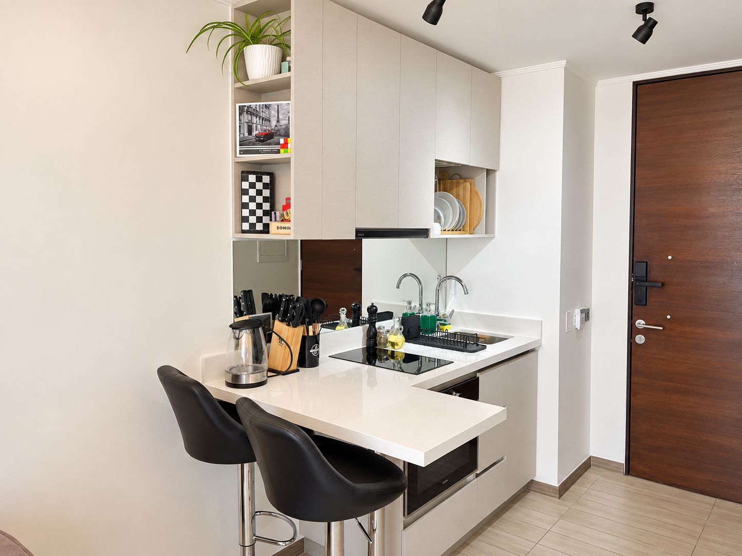 A modern kitchen with white cabinets, a black countertop, and two black bar stools.